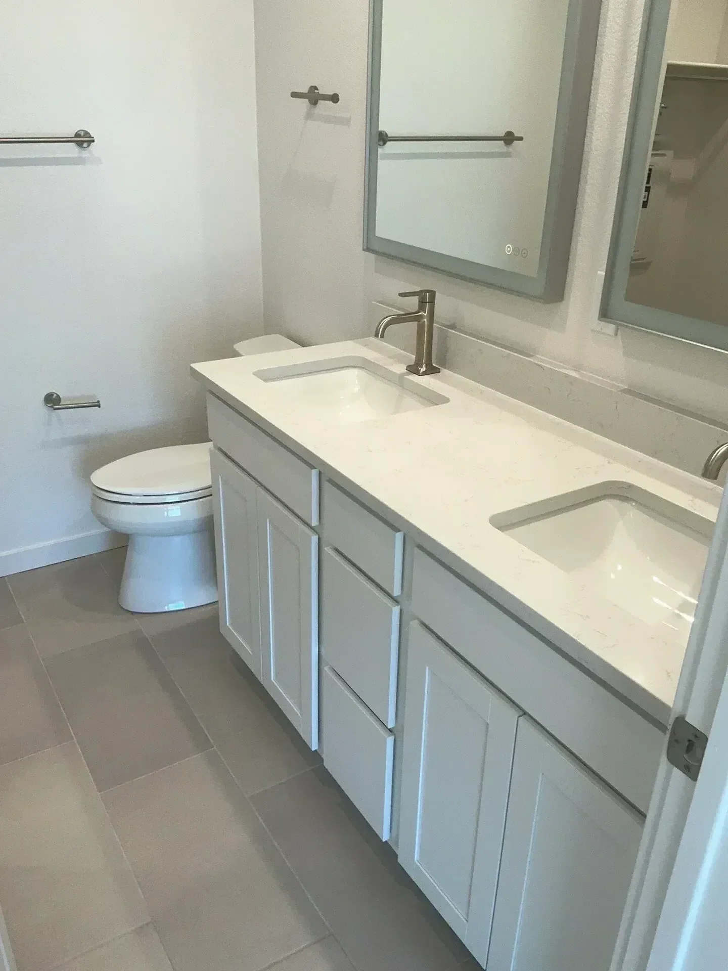Gray bathroom vanity with white quartz countertop, frameless mirror, and integrated LED lighting