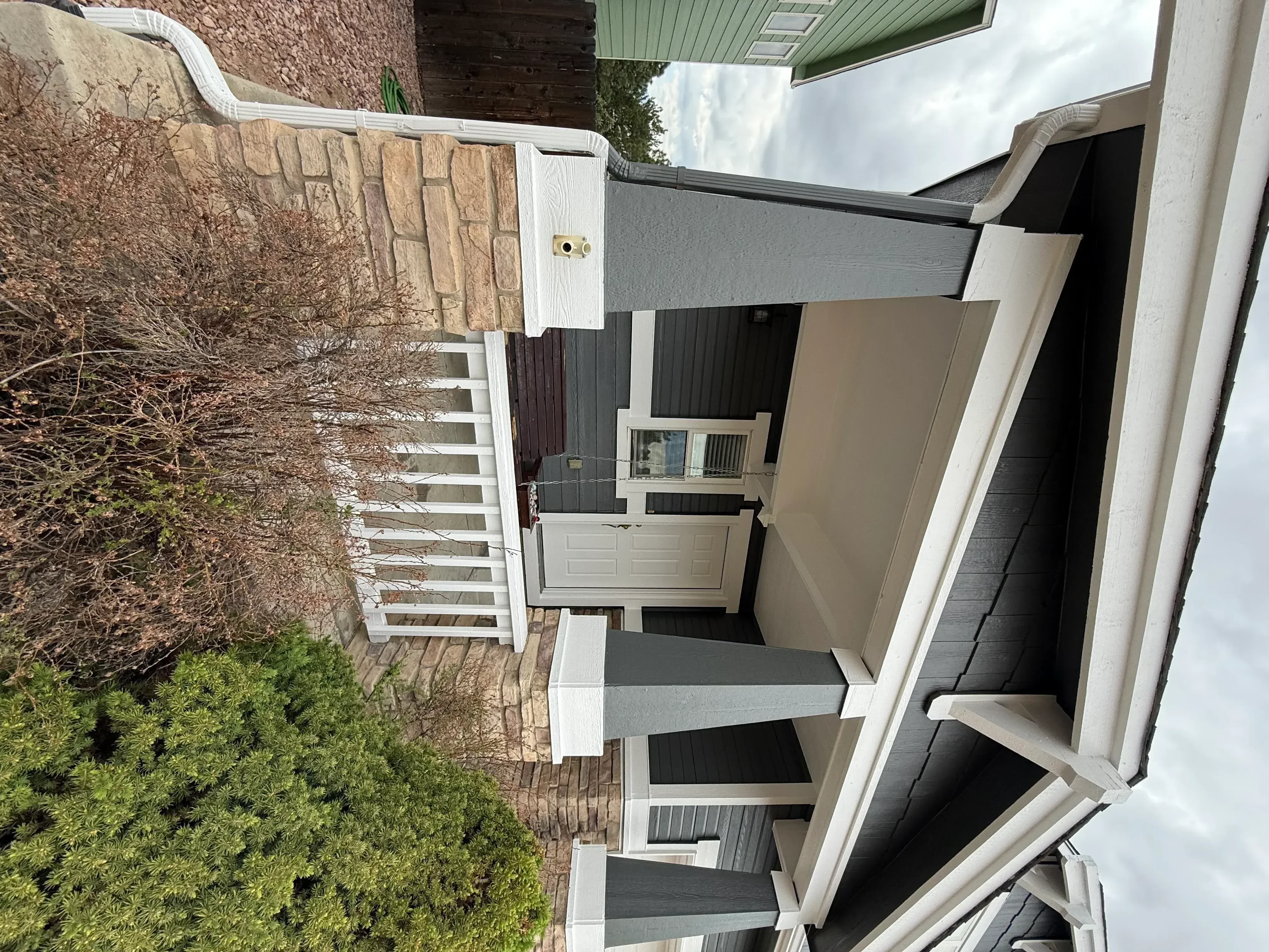 Stone veneer exterior with white trim, new siding, and landscaping