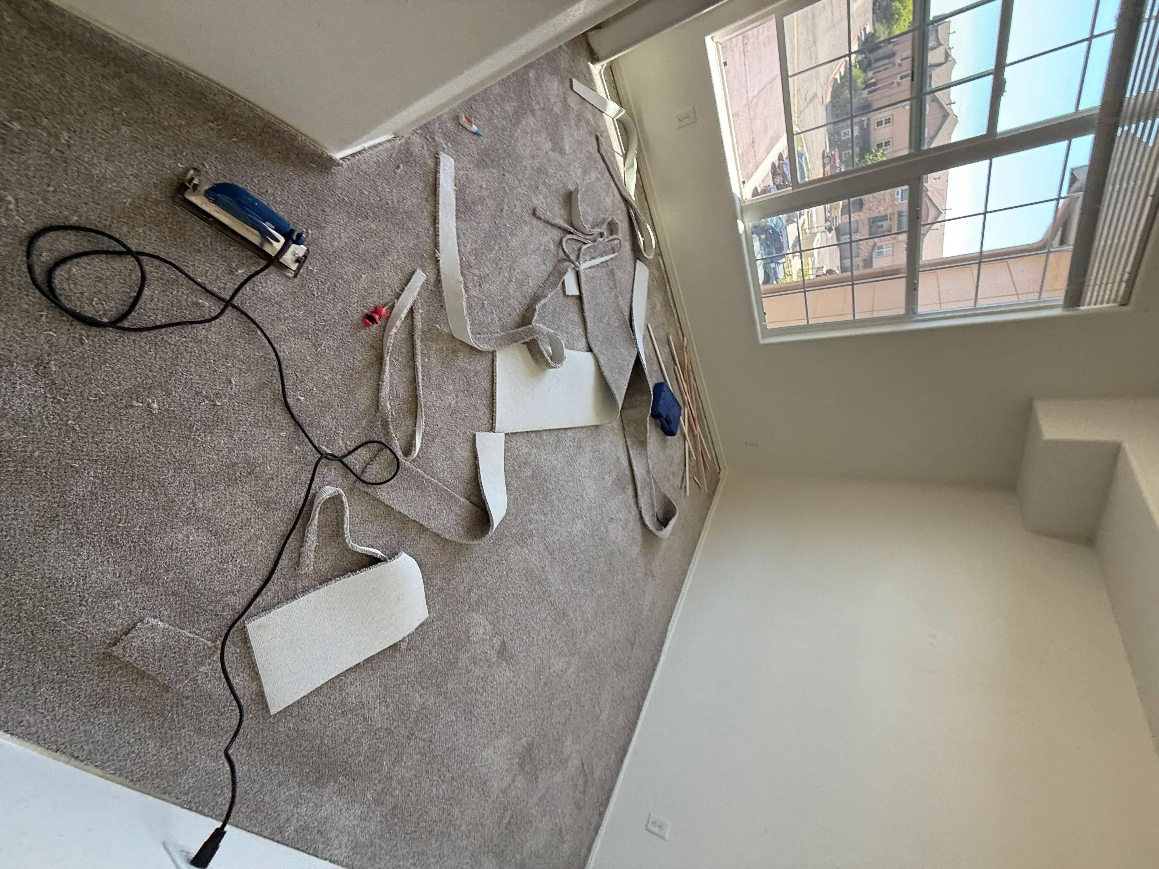 Gray carpet installation with white protective coverings and equipment on floor