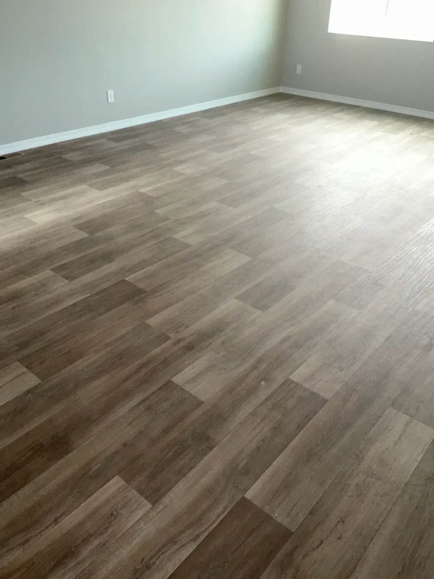 Herringbone pattern luxury vinyl plank flooring in medium brown wood tone