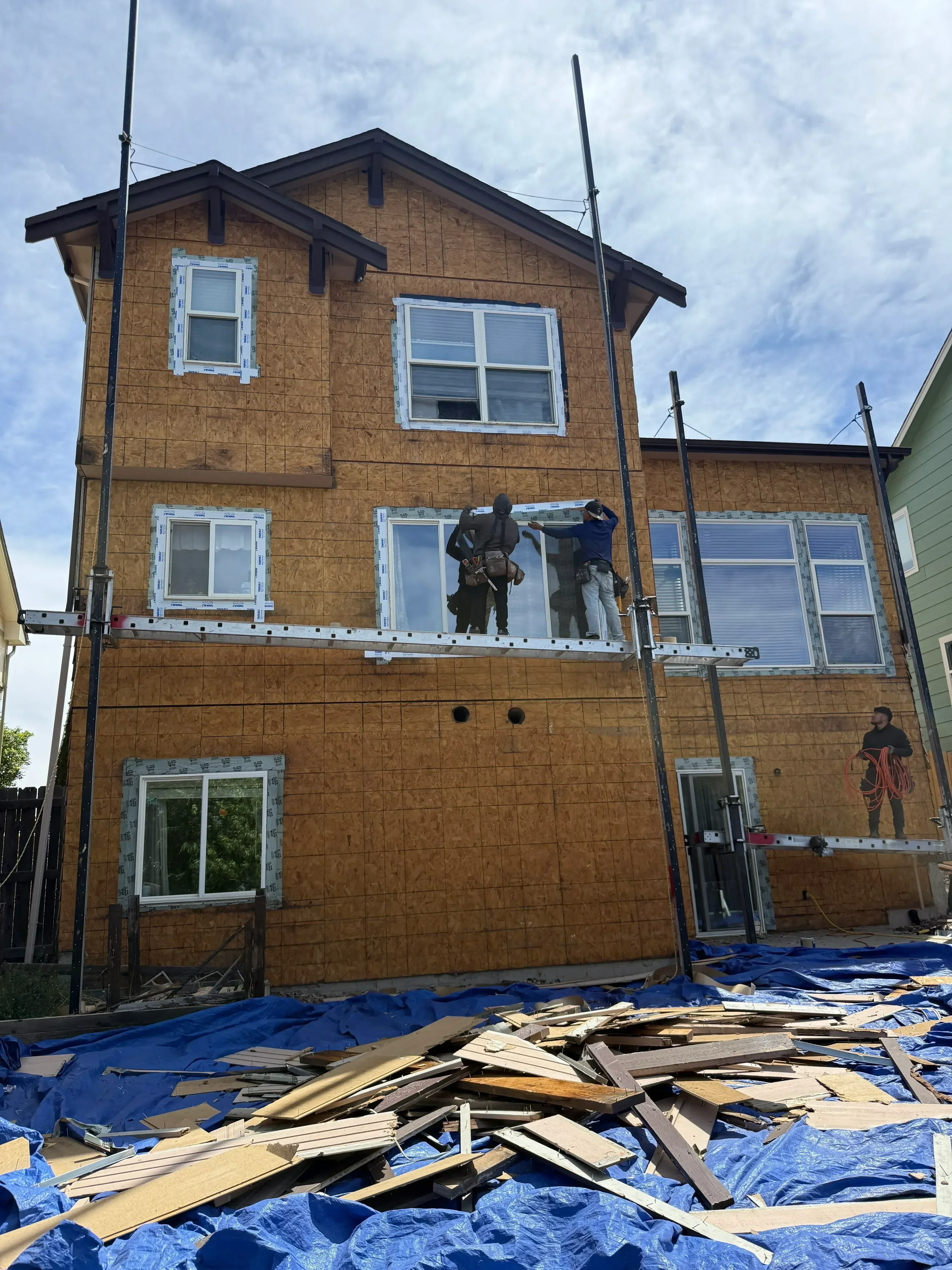 White vinyl windows installed in brick home exterior with protective coverings