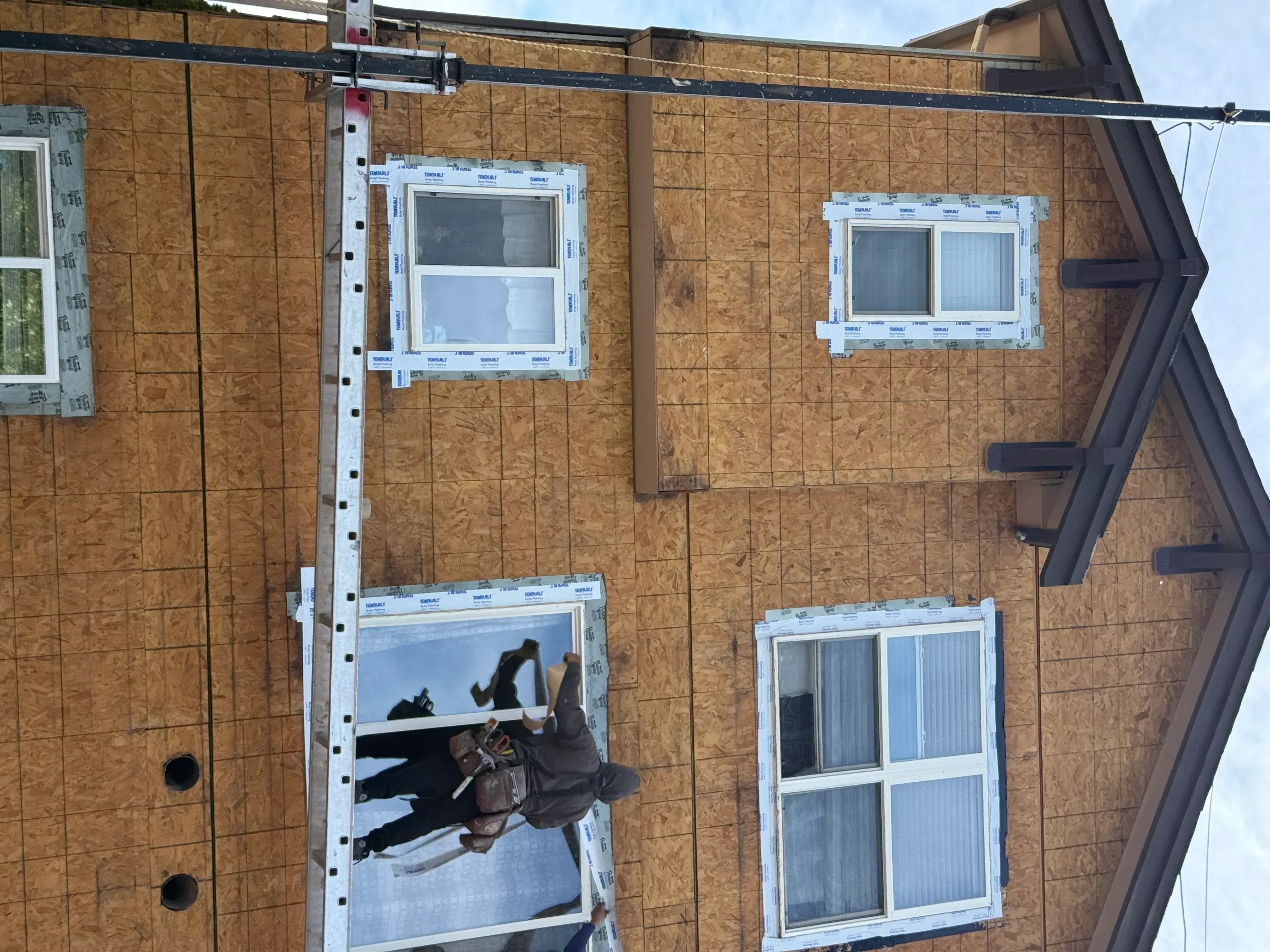 White vinyl windows installed in OSB sheathing with flashing tape and weatherproofing