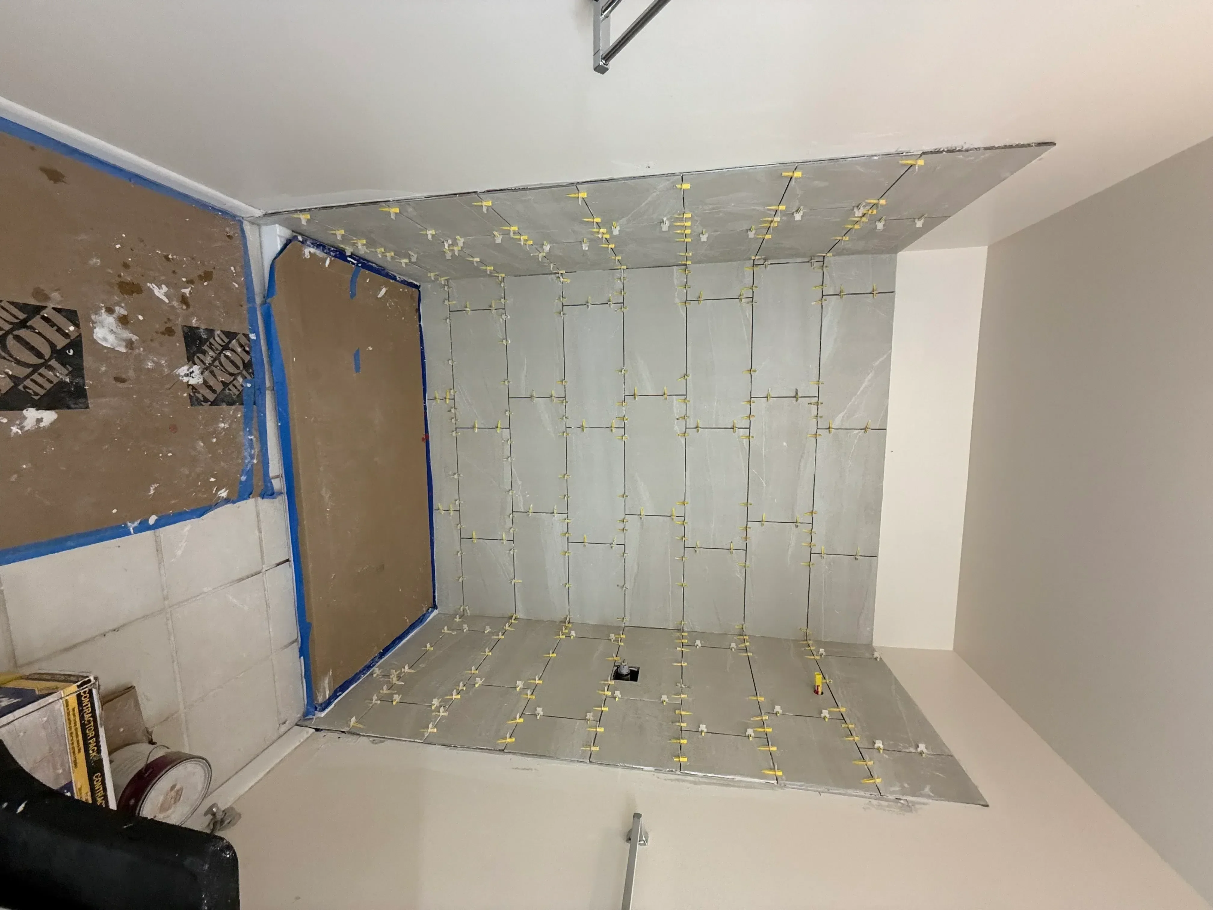 Drywall ceiling installation with brass fasteners and protective sheeting in kitchen space