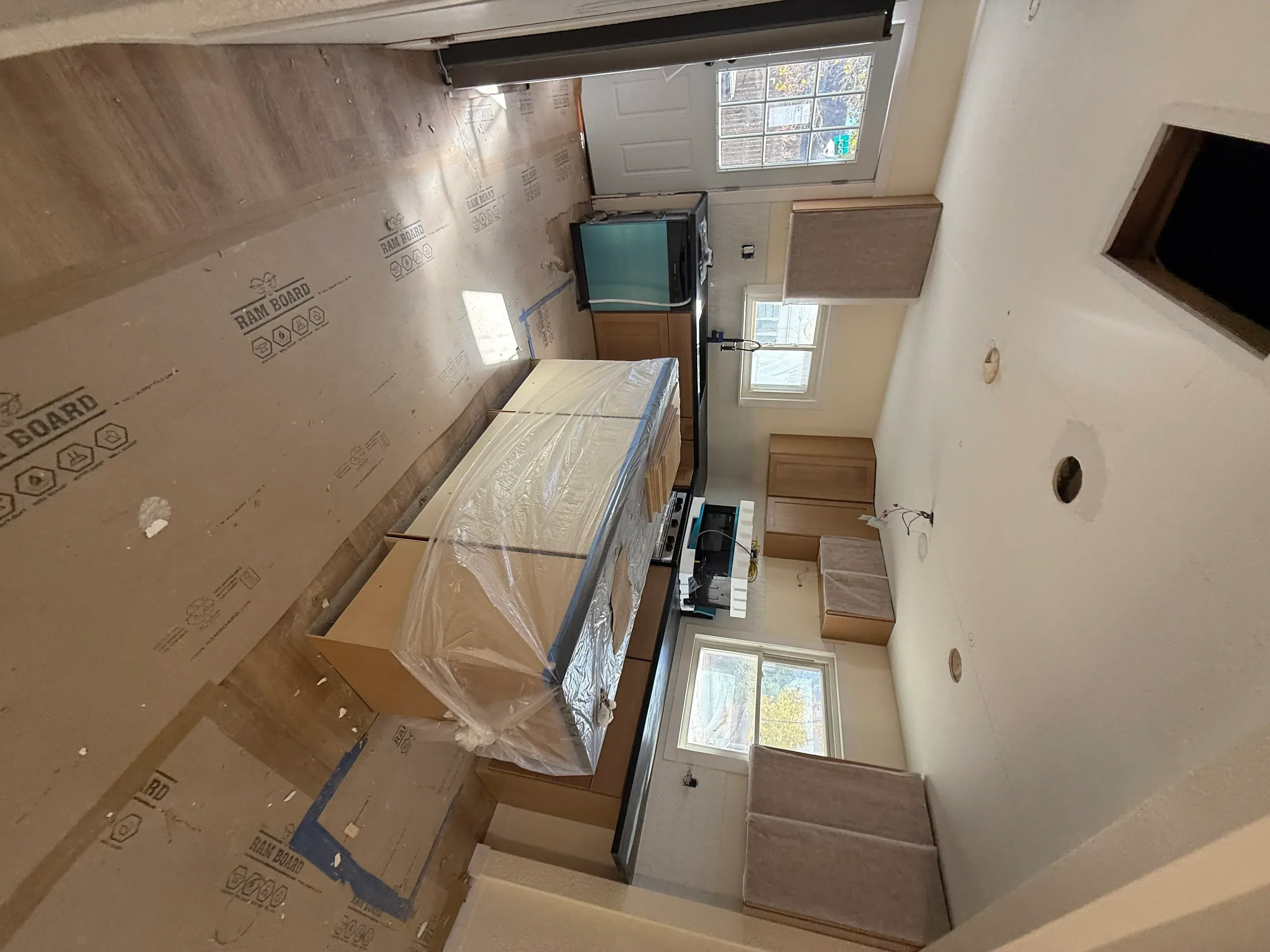 Kitchen renovation with drywall, protective coverings, and framing in progress