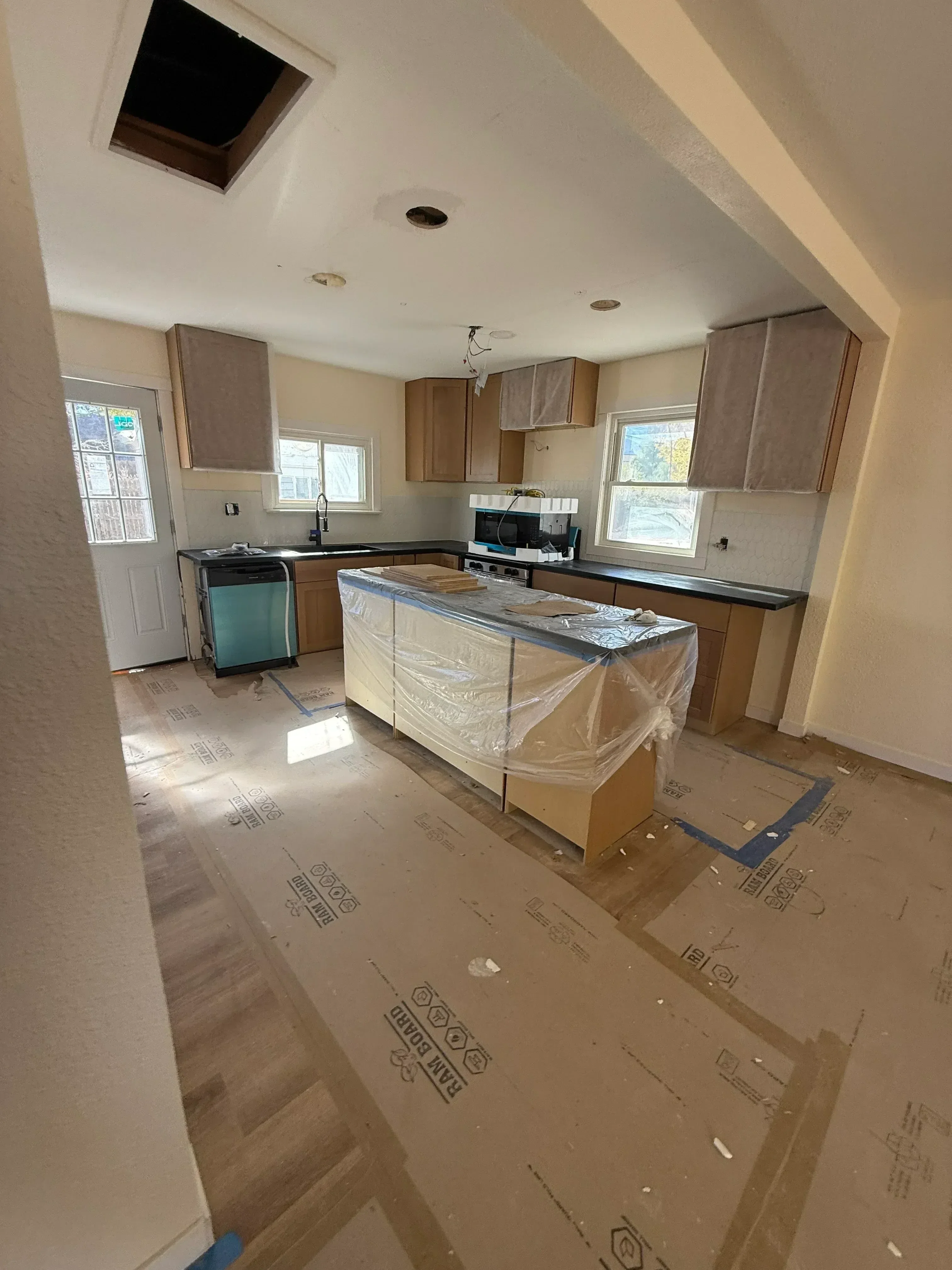 Kitchen remodel in progress with custom wood cabinets, drywall, and new window treatments