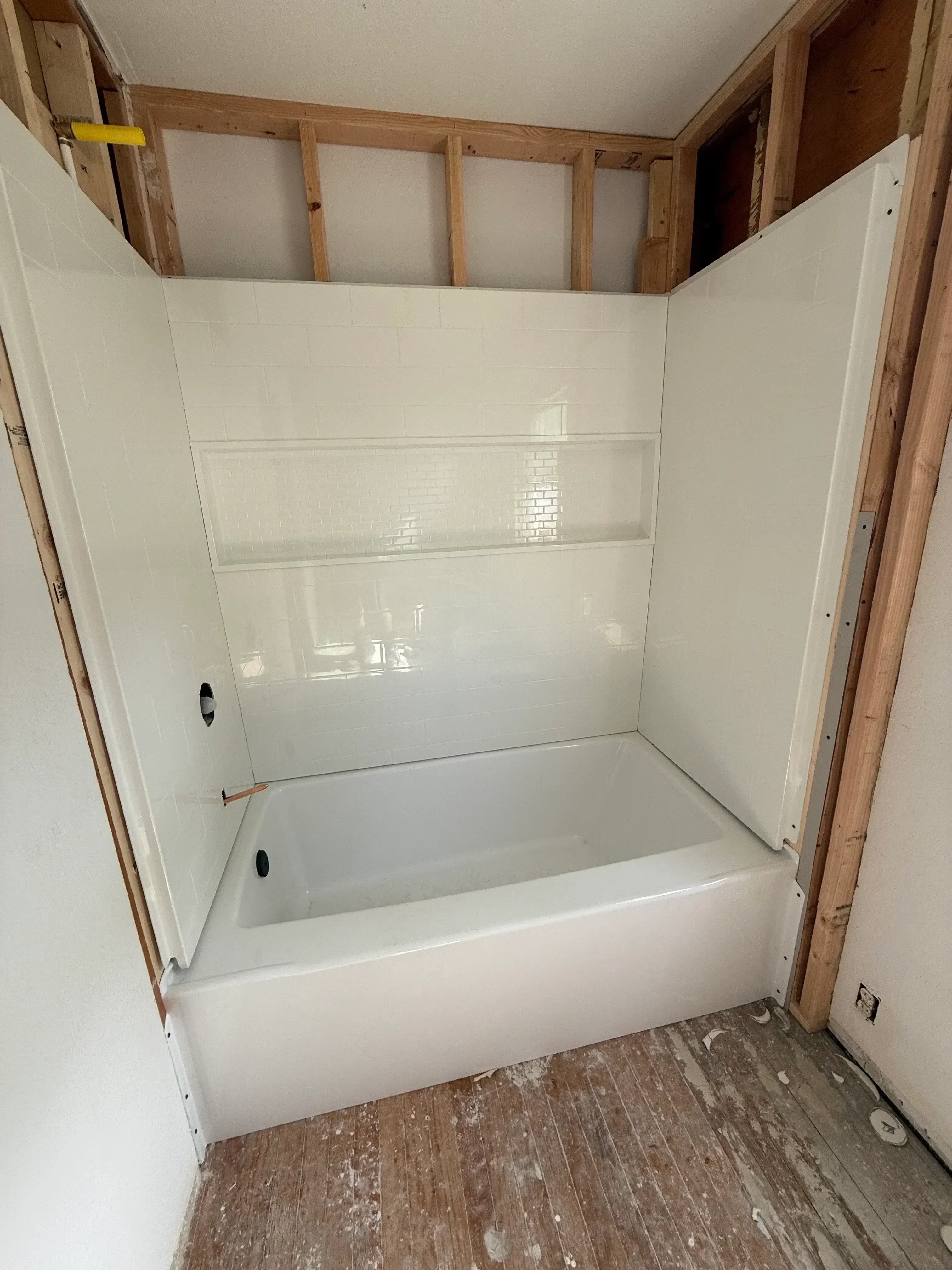Frameless glass shower enclosure with white subway tile walls and built-in bench
