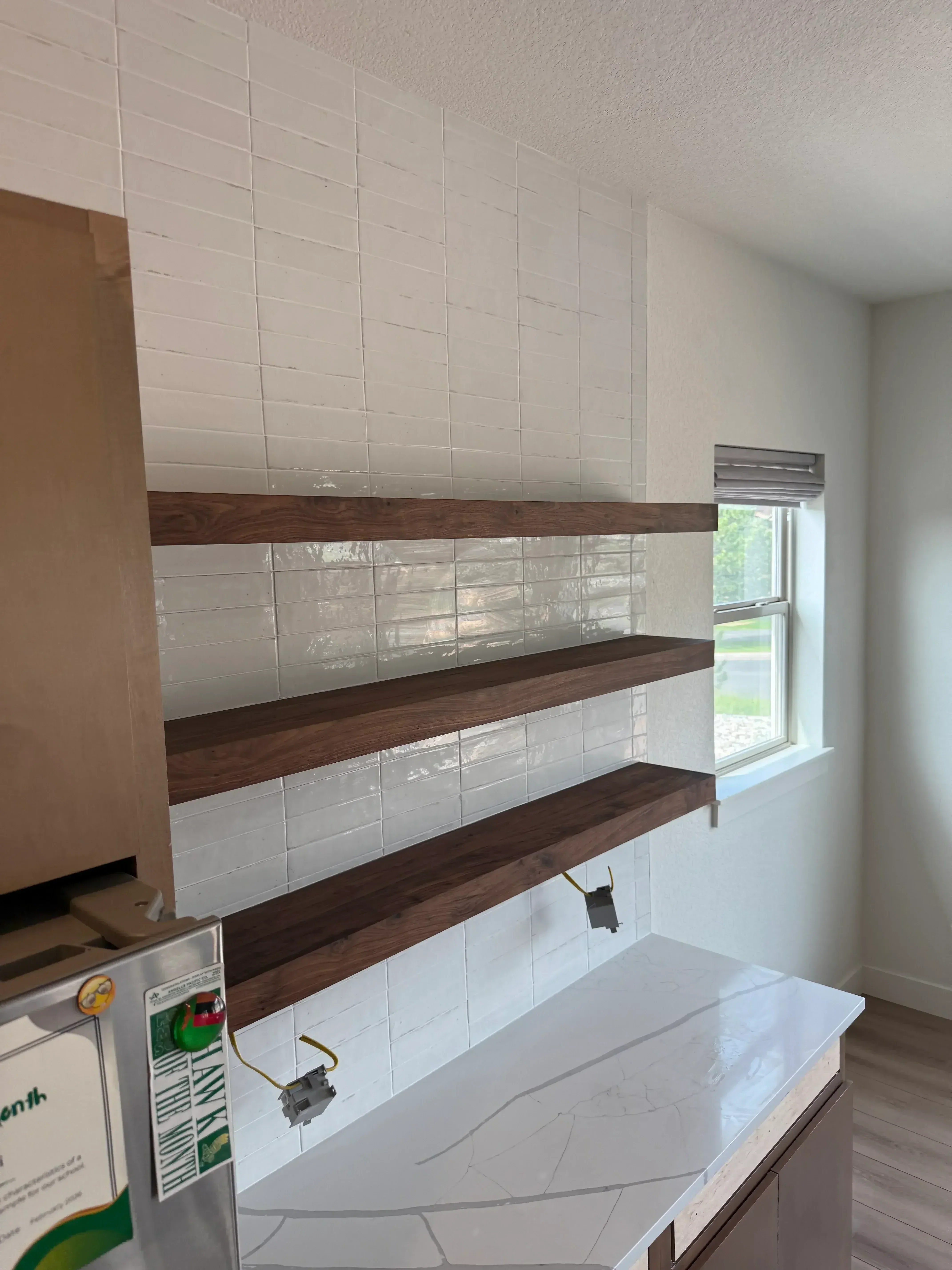 Kitchen renovation with gray ceramic tile flooring and dark wood cabinetry with glass doors