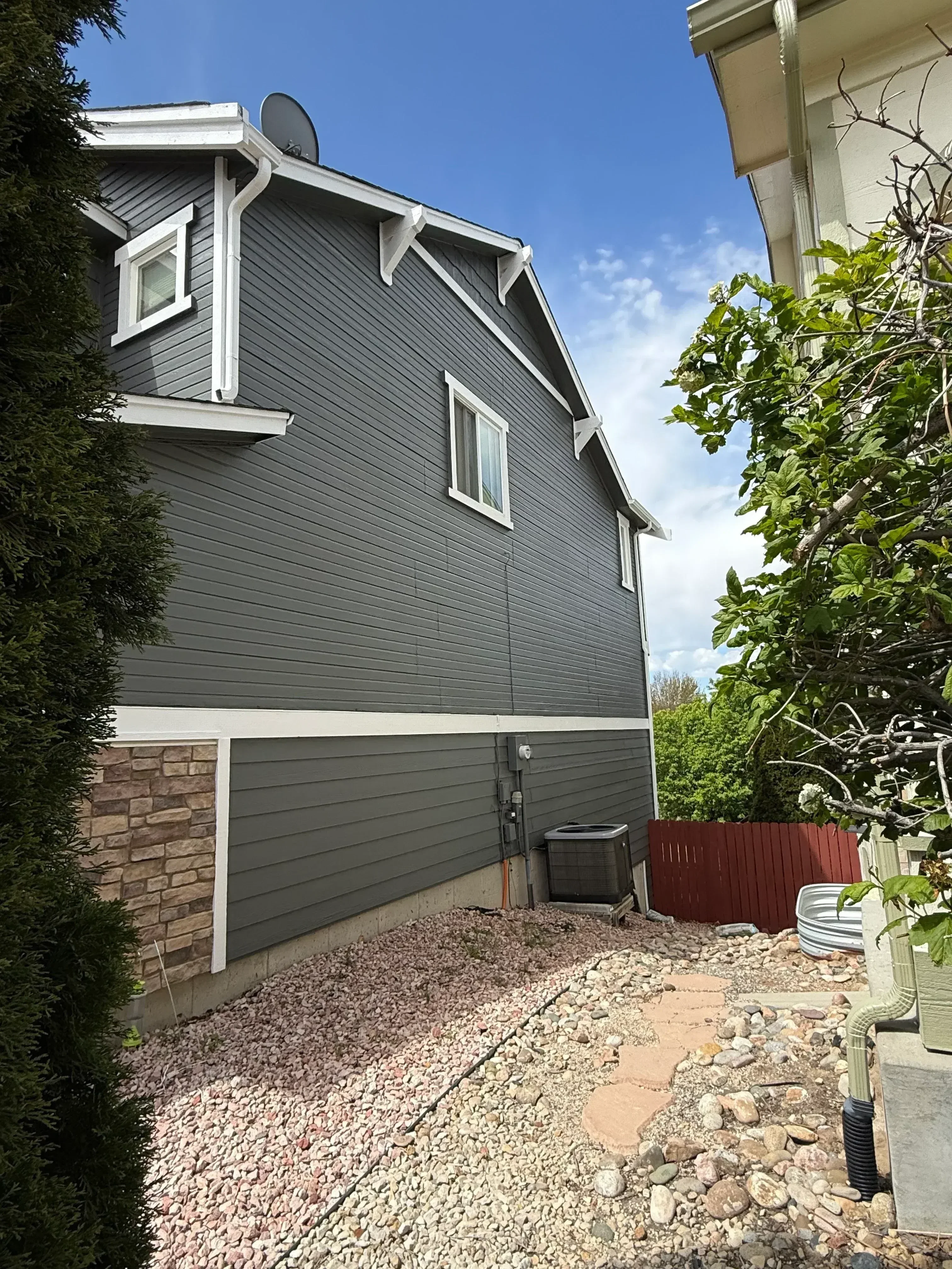 Charcoal metal standing seam roof with white trim, skylights, and gutter system on residential home