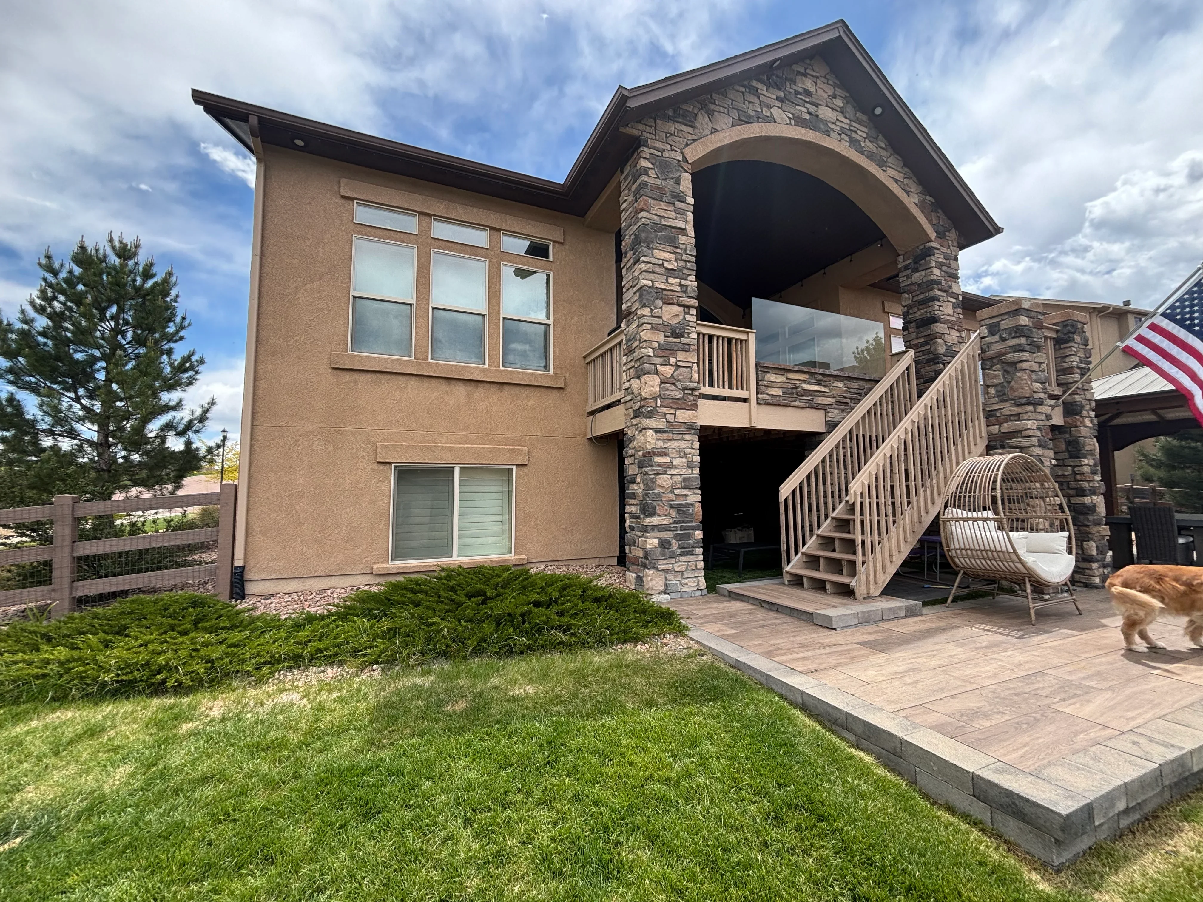 Stacked stone archway, composite deck, aluminum railings, and paver patio on residential exterior