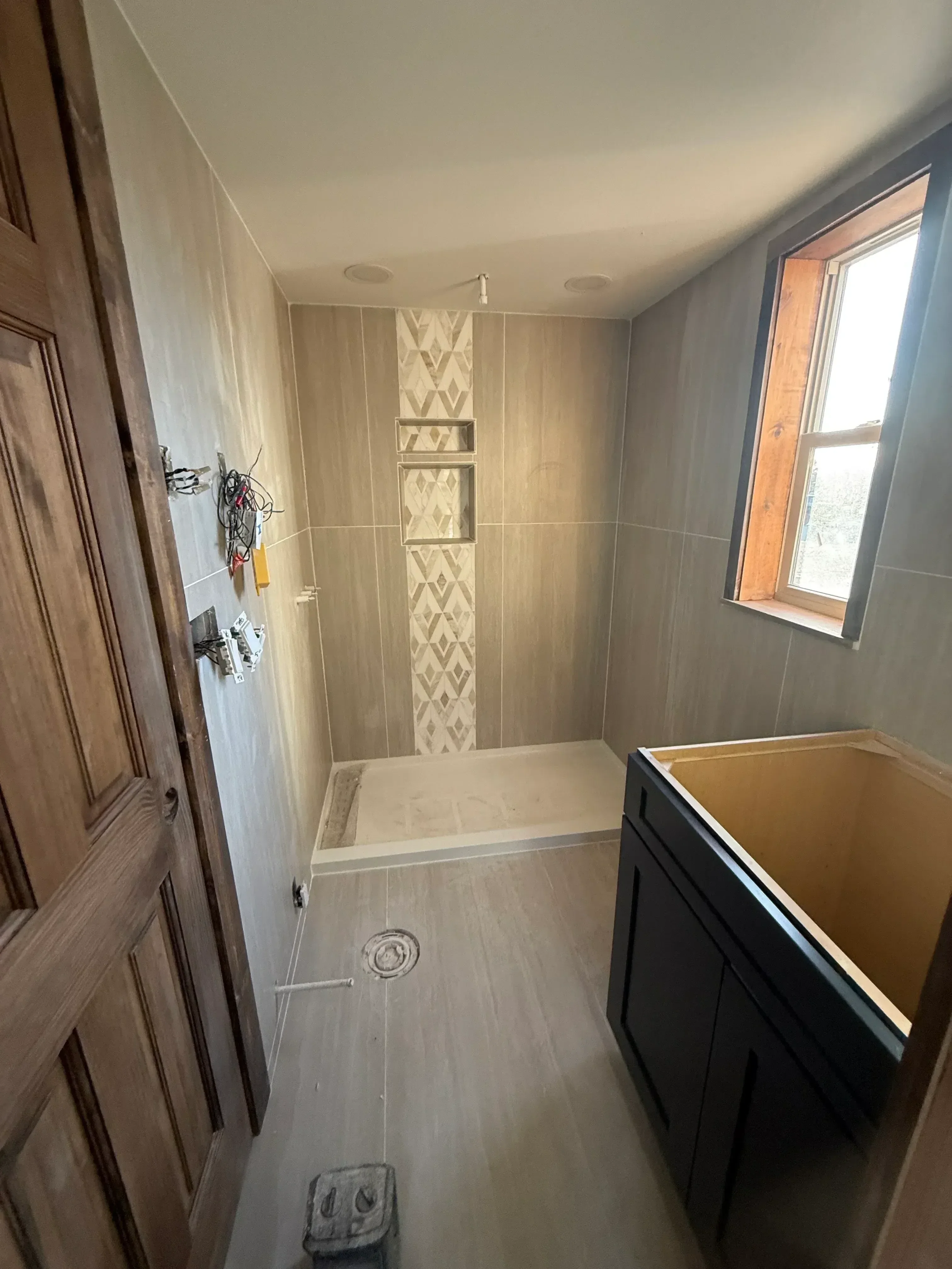Bathroom under construction with porcelain tile walls, geometric border, and skylight